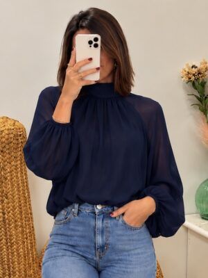 Camisa elegante y femenina de tejido ligero, con cuello alto, mangas abullonadas y preciosa lazada en la espalda. Un diseño versátil y sofisticado, perfecto para combinar tanto con vaqueros como con pantalón de vestir. Disponible en blanco, negro y azul marino.